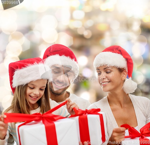 Image of happy family in santa helper hats with gift boxes