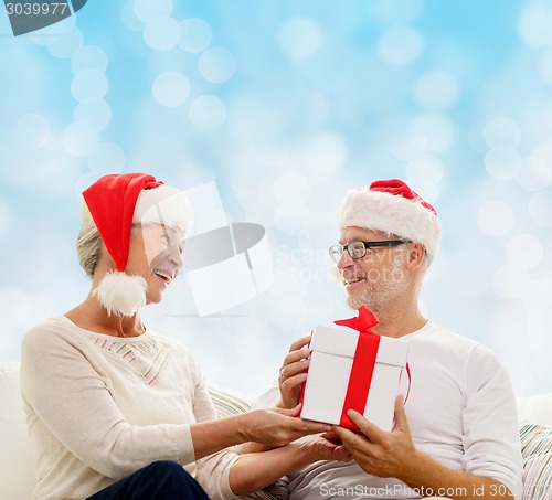 Image of happy senior couple with gift box at home