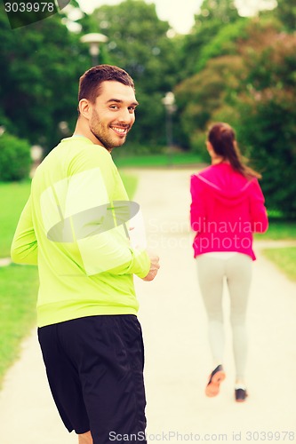 Image of smiling couple running outdoors