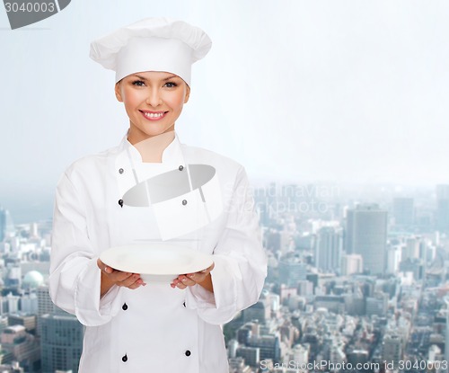 Image of smiling female chef with empty plate