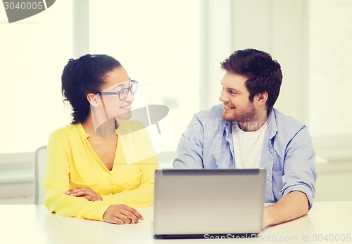 Image of two smiling people with laptop in office