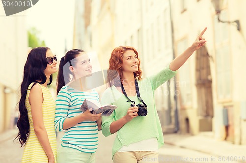 Image of smiling teenage girls with city guide and camera