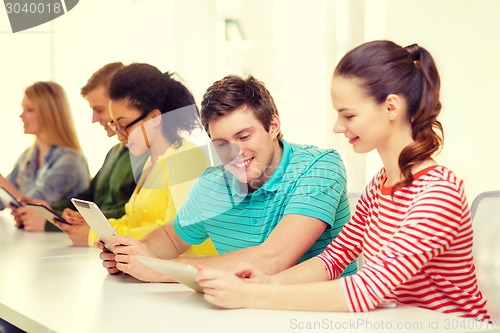 Image of smiling students looking at tablet pc at school