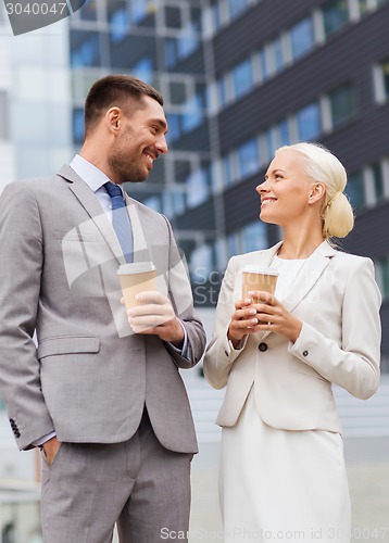 Image of smiling businessmen with paper cups outdoors