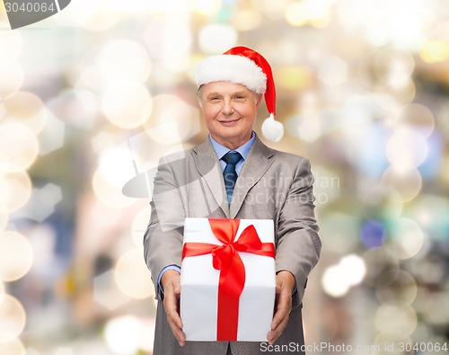 Image of smiling man in suit and santa helper hat with gift