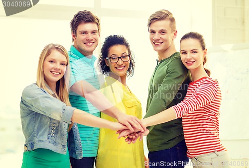Image of smiling students with hands on top of each other