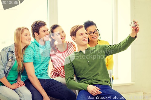 Image of five smiling students taking picture with camera