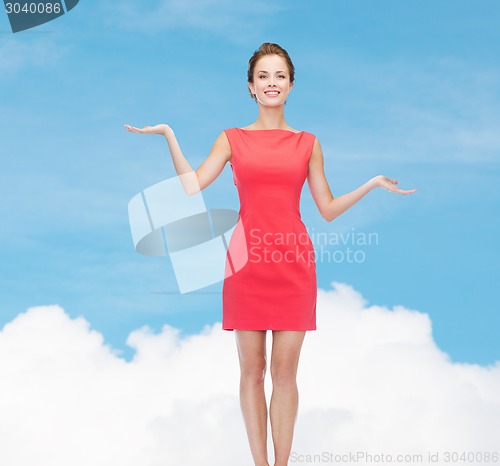 Image of smiling young woman in dress holding something