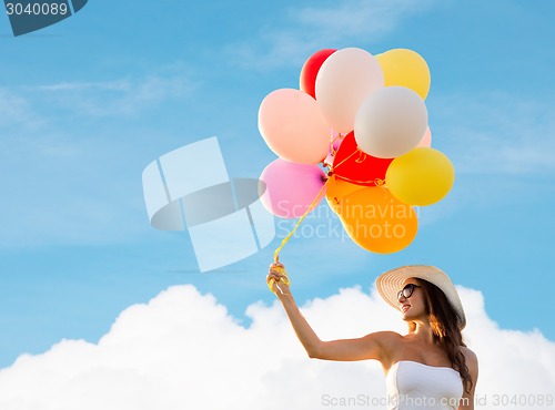 Image of smiling young woman in sunglasses with balloons