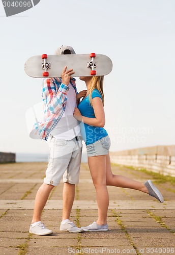 Image of couple with skateboard kissing outdoors