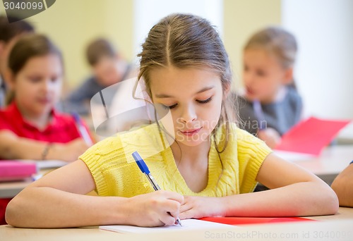 Image of group of school kids writing test in classroom