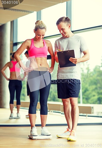Image of smiling man and woman with scales in gym