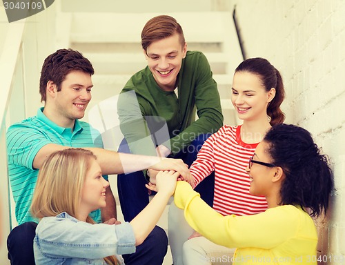 Image of smiling students with hands on top of each other