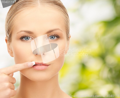 Image of beautiful young woman pointing finger to her lips