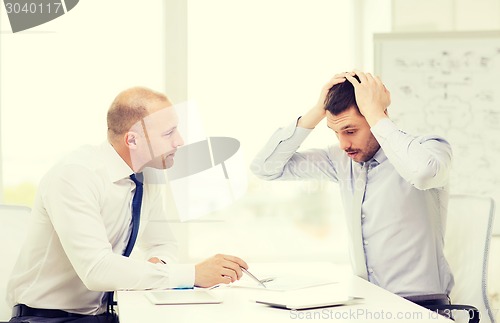 Image of two serious businessmen with tablet pc in office