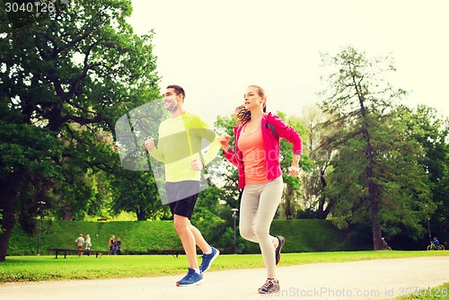 Image of smiling couple with earphones running outdoors