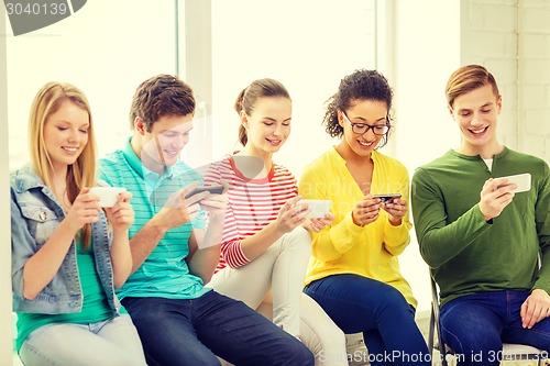 Image of smiling students with smartphone texting at school