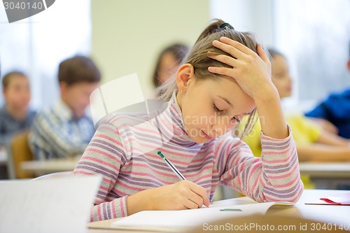 Image of group of school kids writing test in classroom