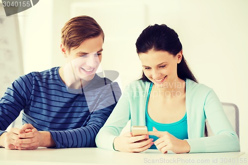 Image of two smiling students with smartphone at school