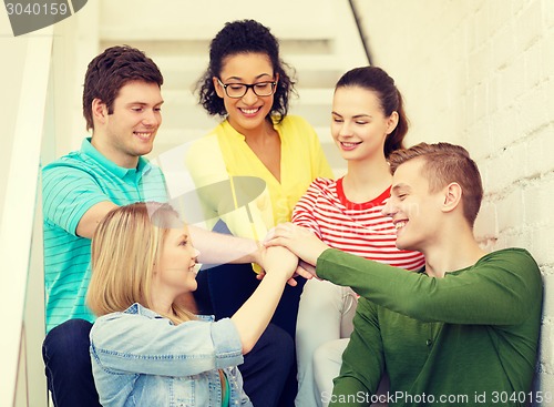 Image of smiling students with hands on top of each other