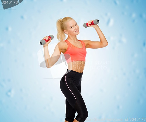 Image of smiling beautiful sporty woman with dumbbells