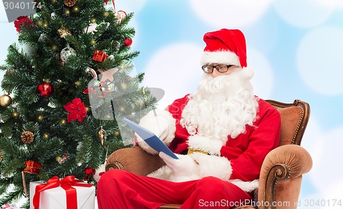 Image of man in costume of santa claus with tablet pc