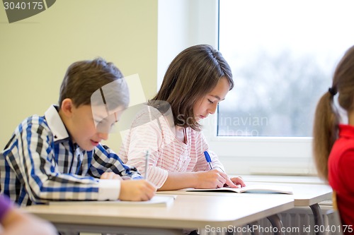 Image of group of school kids writing test in classroom