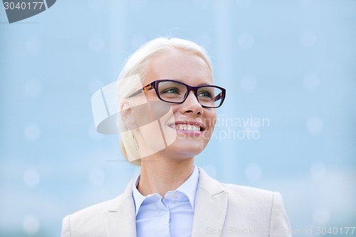 Image of young smiling businesswoman over office building