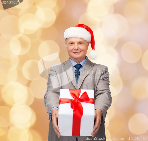 Image of smiling man in suit and santa helper hat with gift