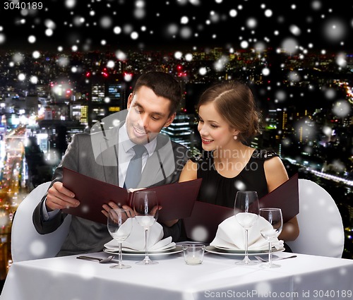 Image of smiling couple with menus at restaurant