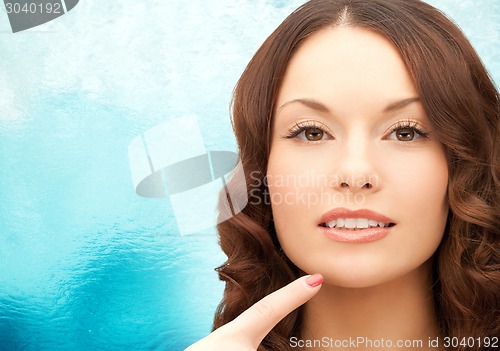 Image of beautiful young woman pointing finger to her chin