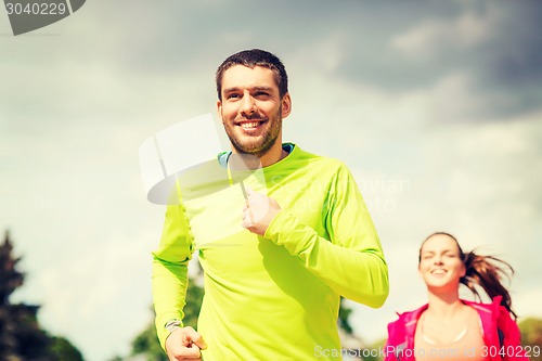 Image of smiling couple running outdoors