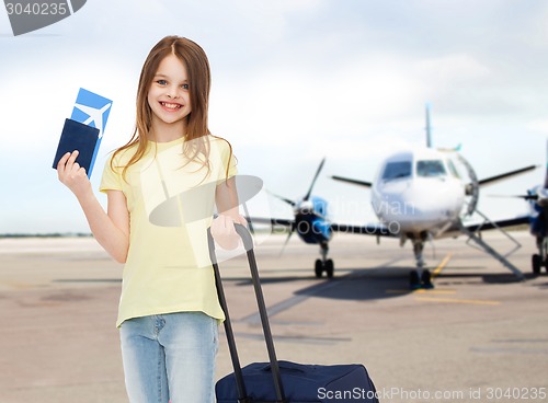 Image of smiling girl with travel bag ticket and passport