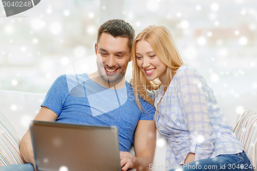 Image of smiling happy couple with laptop at home