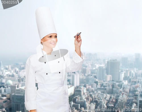 Image of smiling female chef writing something on air