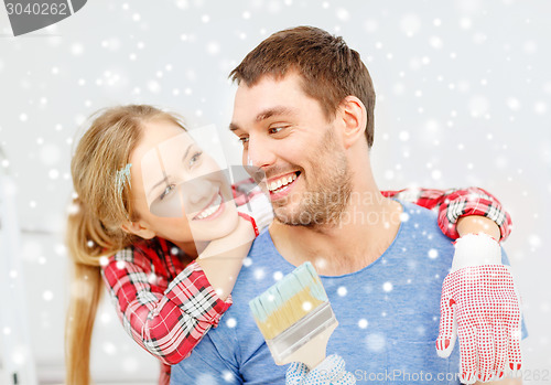Image of smiling couple with paintbrush at home