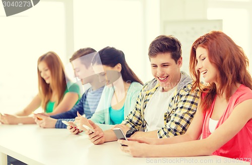 Image of smiling students with smartphones at school