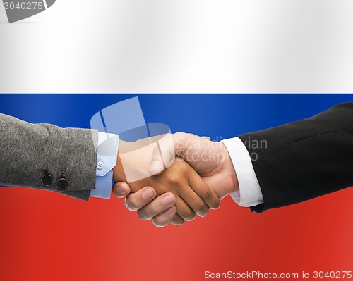 Image of close up of handshake over russian flag