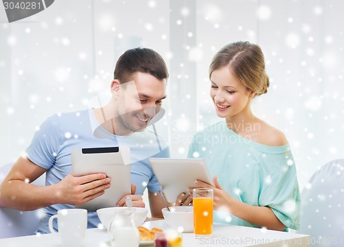 Image of smiling couple with tablet pc having breakfast