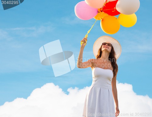 Image of smiling young woman in sunglasses with balloons