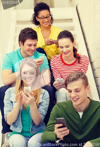 Image of smiling students with smartphone texting at school