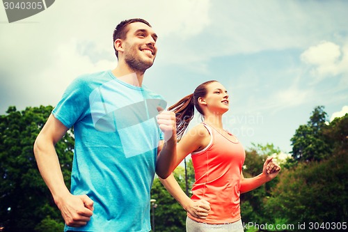 Image of smiling couple running outdoors
