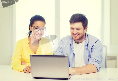 Image of two smiling people with laptop in office