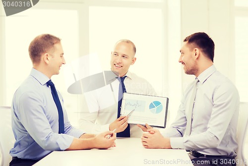 Image of smiling businessmen with papers in office