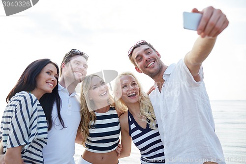Image of happy friends on beach and taking selfie