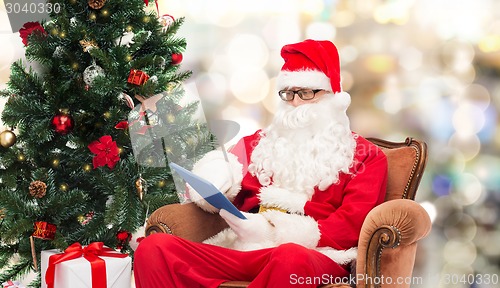 Image of man in costume of santa claus with tablet pc