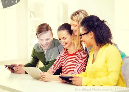 Image of smiling students looking at tablet pc at school