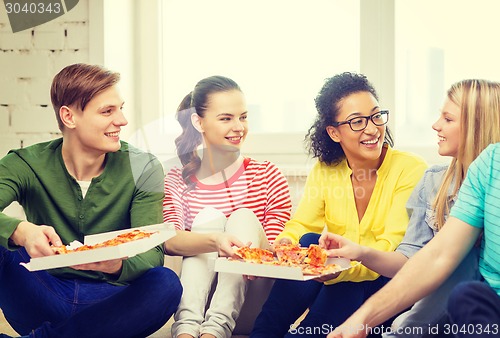 Image of five smiling teenagers eating pizza at home