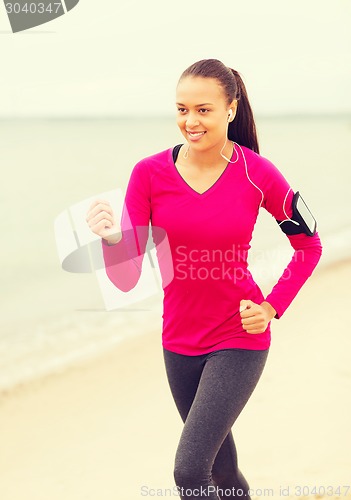 Image of smiling young woman running outdoors
