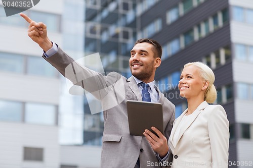 Image of smiling businessmen with tablet pc outdoors